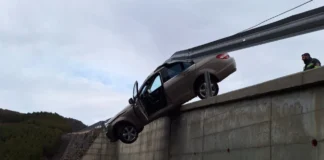 FOTOT/ Aksidenti i frikshëm, makina humb kontrollin dhe qëndron pezull mes barrierës dhe kanalit