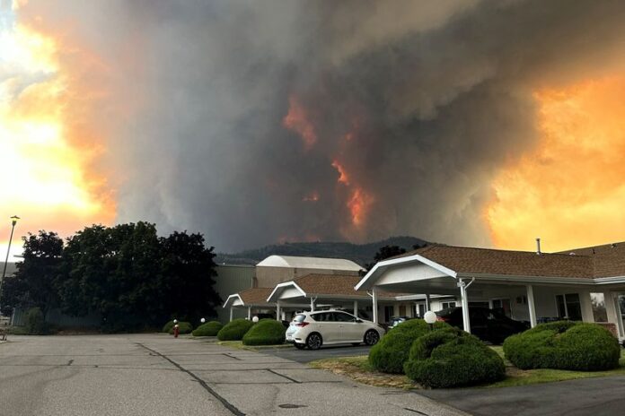 Smoke rises from the Bald Range wildfire over a residential street in Summerland